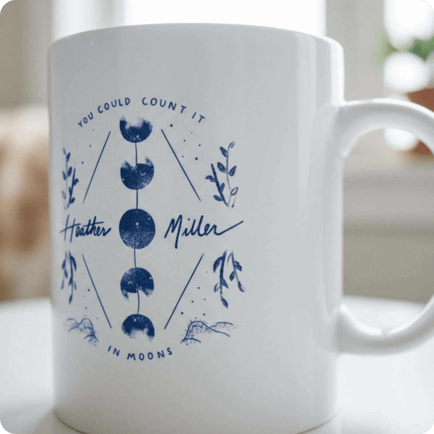 Ceramic mug featuring celestial moon phase illustration with personalized script typography.
