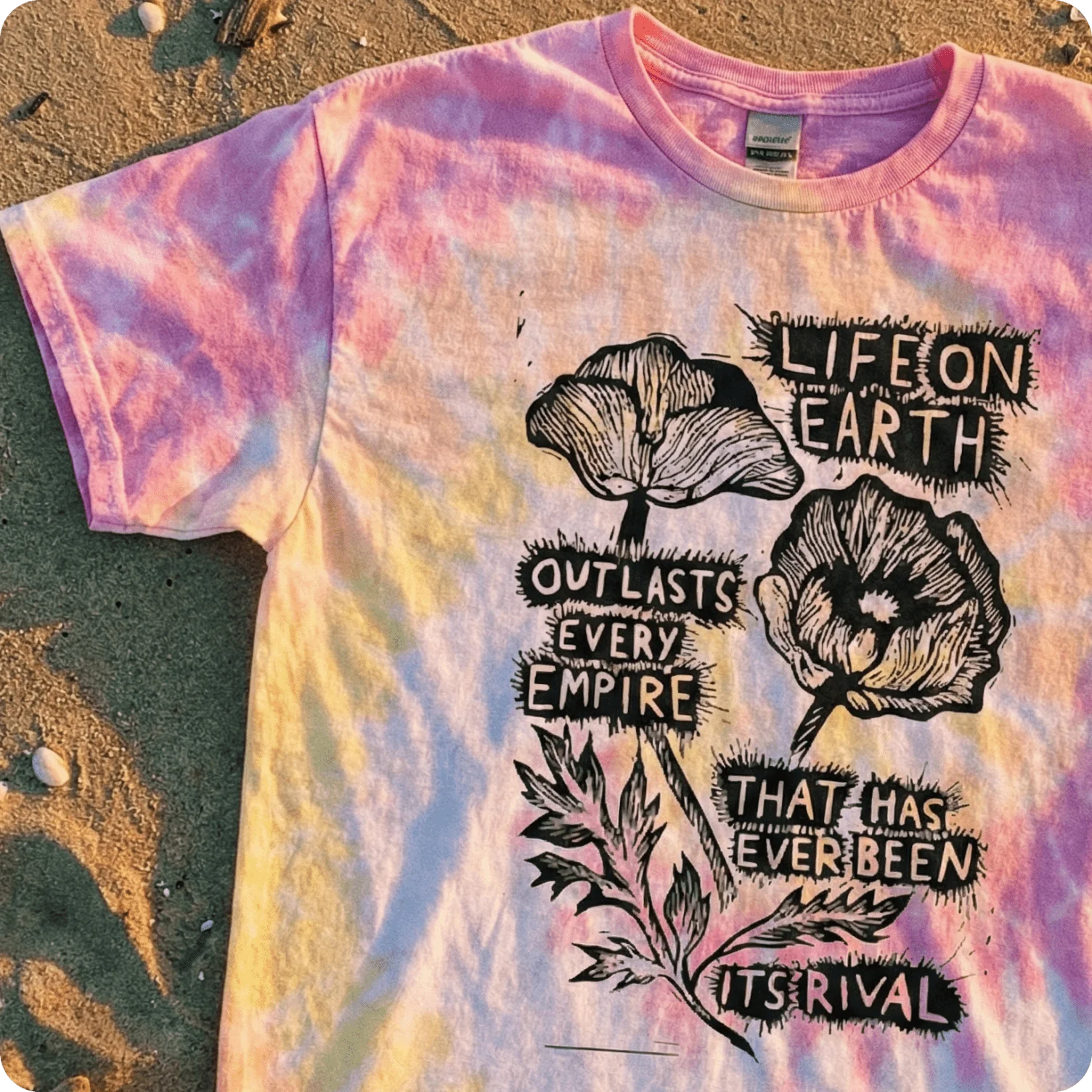 Tie-dye t-shirt featuring linocut-style floral illustration paired with bold protest text.