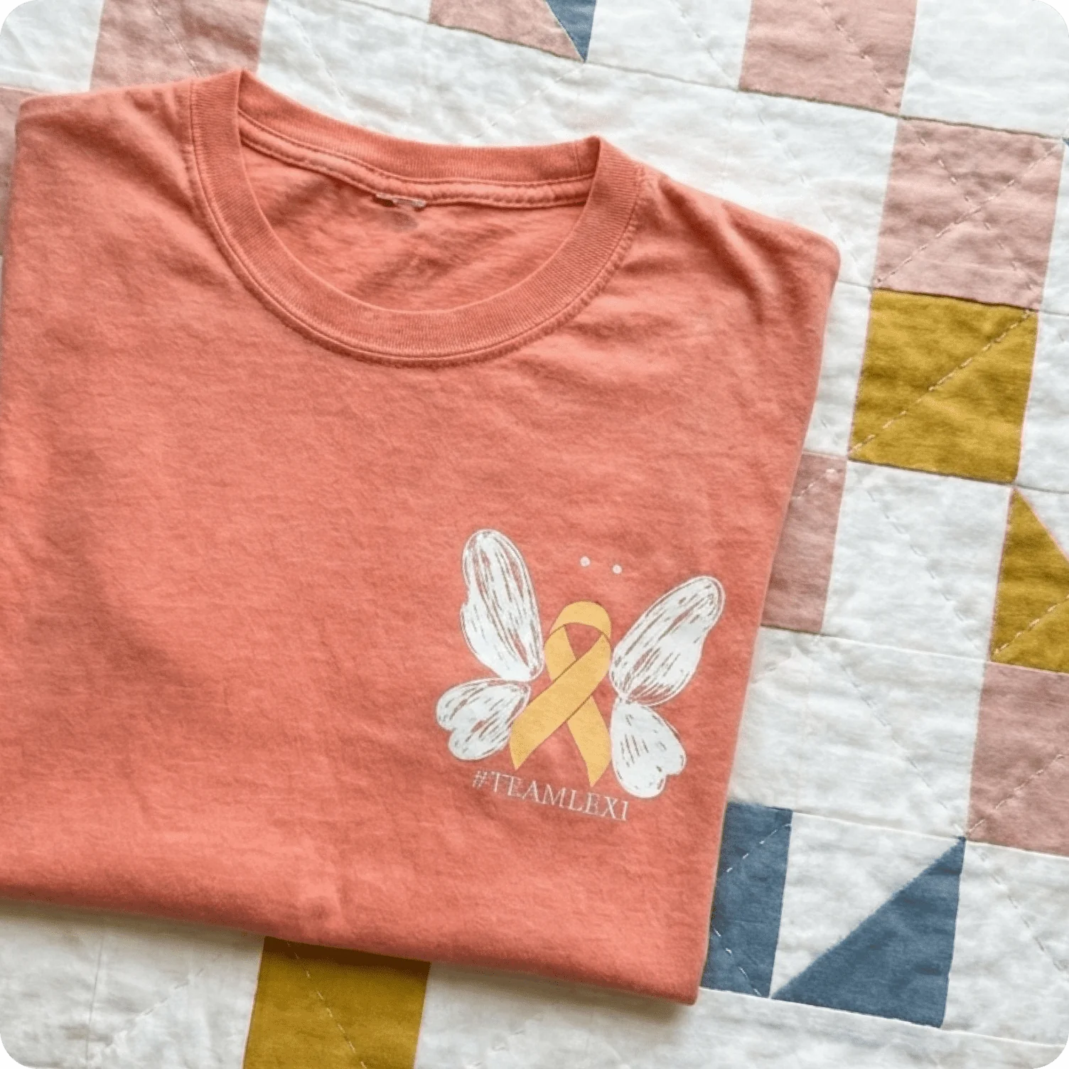 T-shirt featuring small symbolic ribbon graphic used for cause-driven awareness designs.