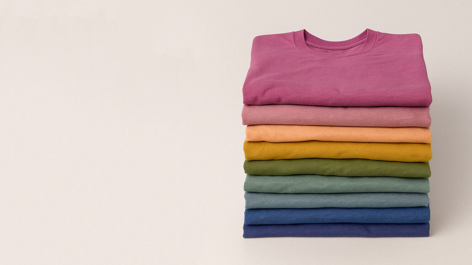 Stack of folded Bella+Canvas t-shirts in pink, peach, yellow, green, blue, and purple.