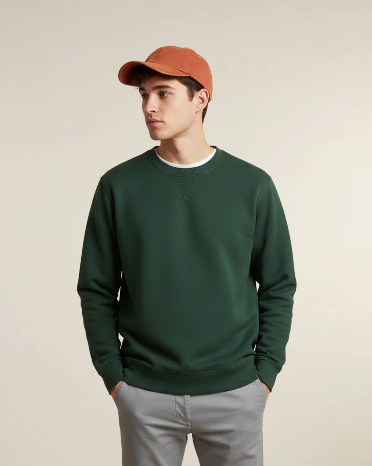 Burnt orange organic cotton baseball cap from Econscious on a model wearing a green sweatshirt.