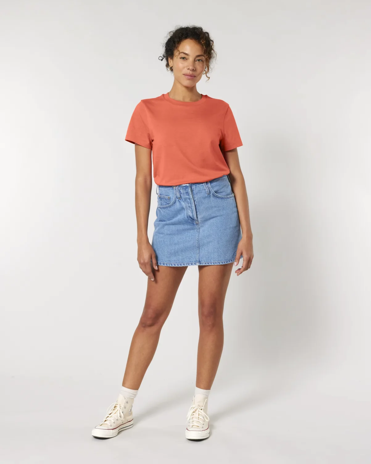 Female model wearing a Stanley/Stella Women's Muser Tee in Fiesta orange.