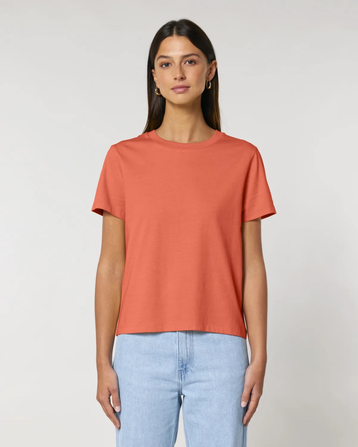 Female model wearing a Stanley/Stella Women's Muser Tee in Fiesta orange.